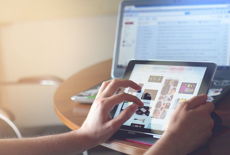 person scrolling through a tablet and checking email