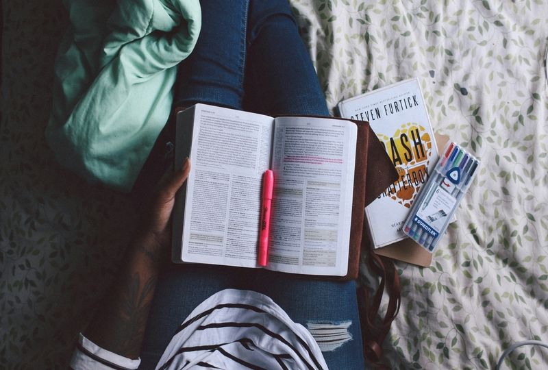 person sitting on the bed, learning new English words and taking notes