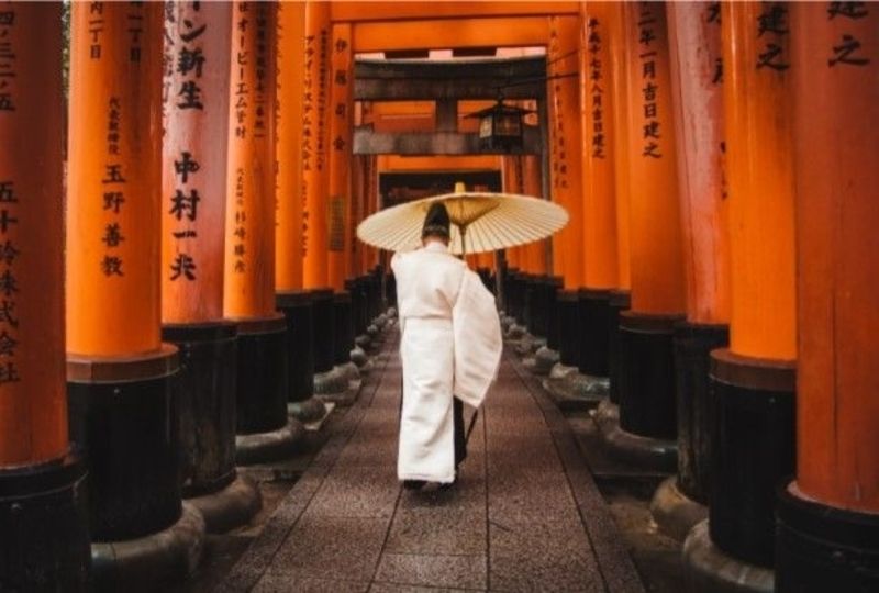 Man walks into a temple with a Japanese unbrella