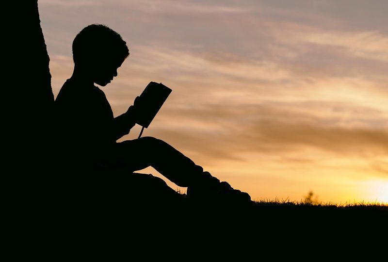 Boy on a mountain reading about Italian grammar