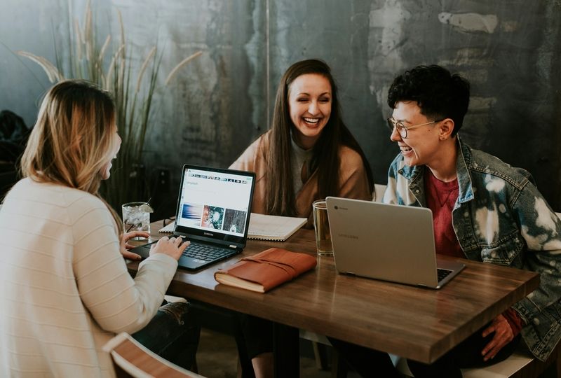 Three adults sitting at the table with laptops