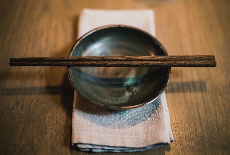 Chopsticks resting on an empty bowl