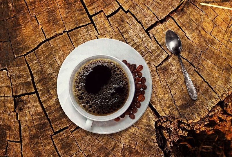 Coffee in a white cup and saucer on a wooden stump