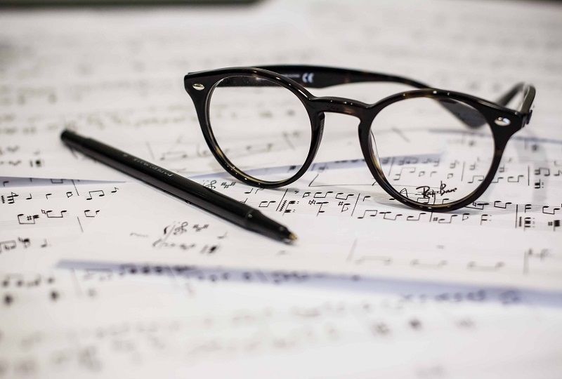 A pair of glasses sitting on some sheet music