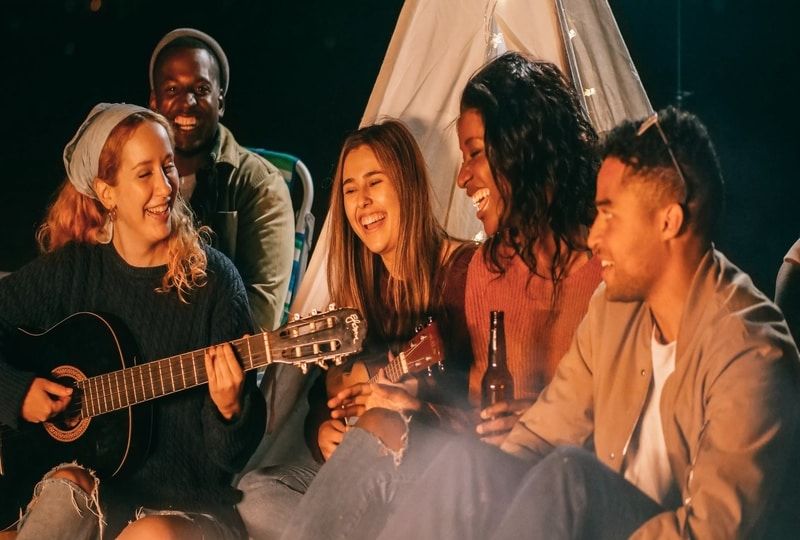 Friends socialising by camp fire