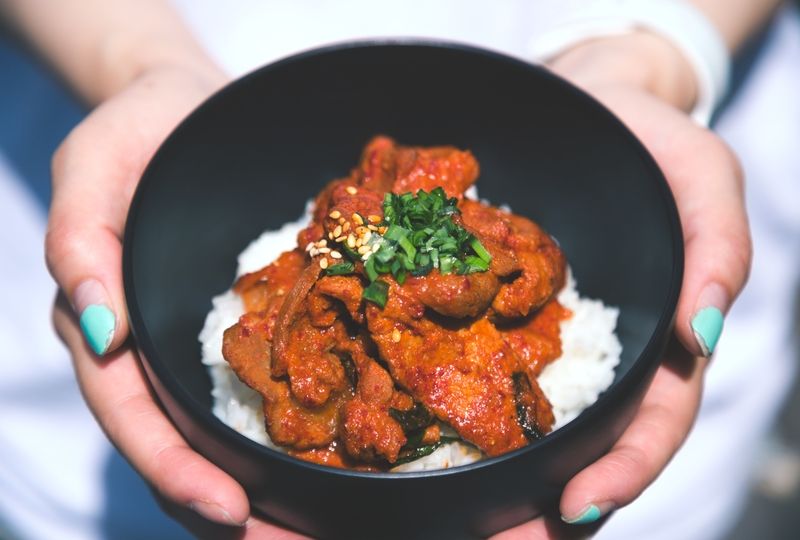 Girl holding bowl of rice and meat