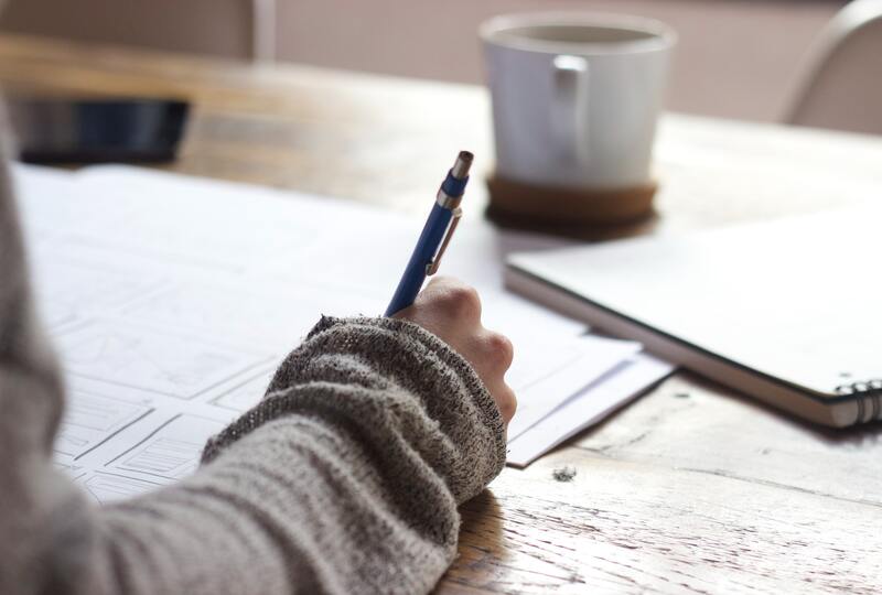 Hand with pen writing in a notebook on a table