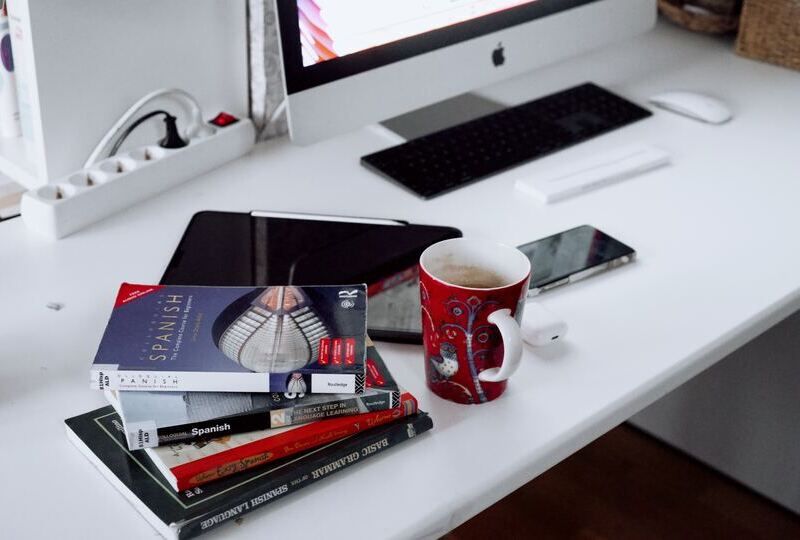 A pile of grammar books near a computer