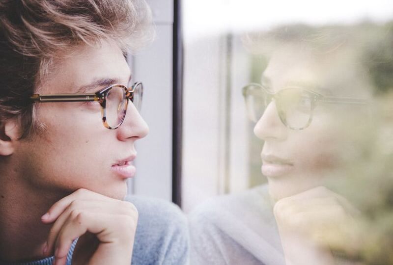 A man looking at his reflection out a window