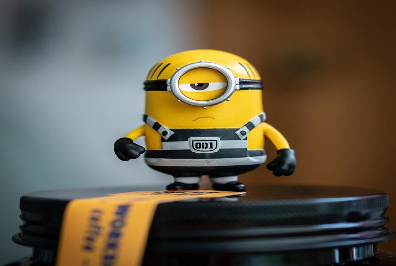 Minion in prison uniform standing on black container