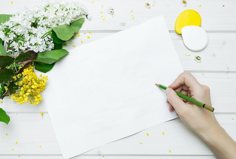 Person writing on a blank piece of paper