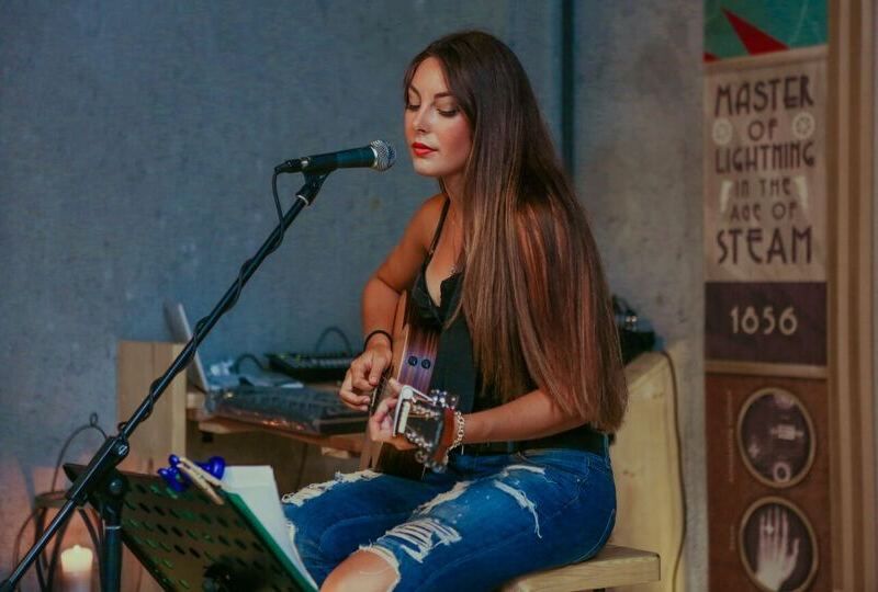 Young woman with a guitar singing publicly