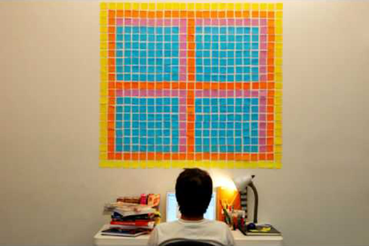 Boy looking at desk looking at wall with post-it notes forming shape of a window