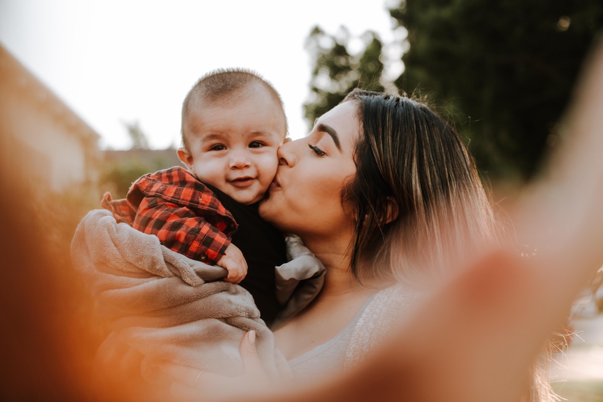 A mother giving a kiss to a boy