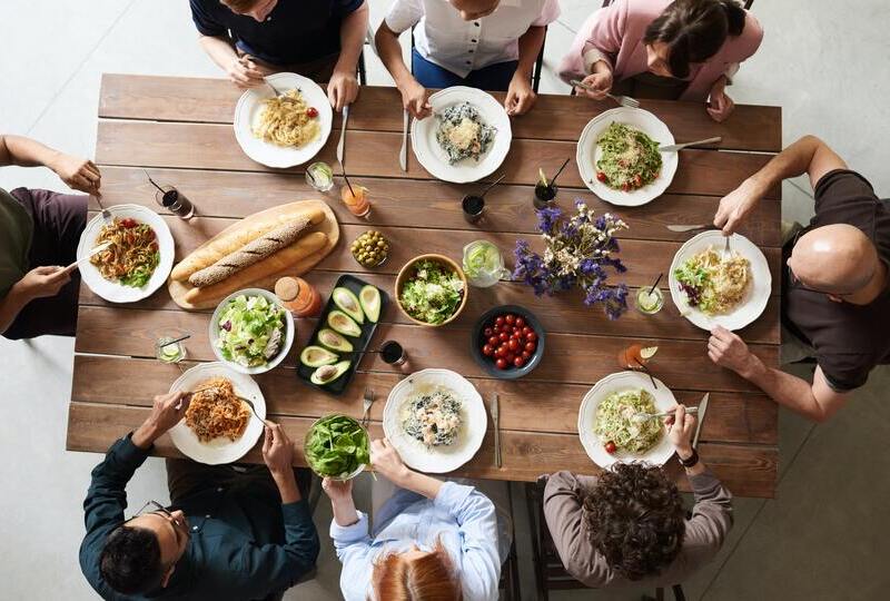 people sitting around table eating lunch with food on table