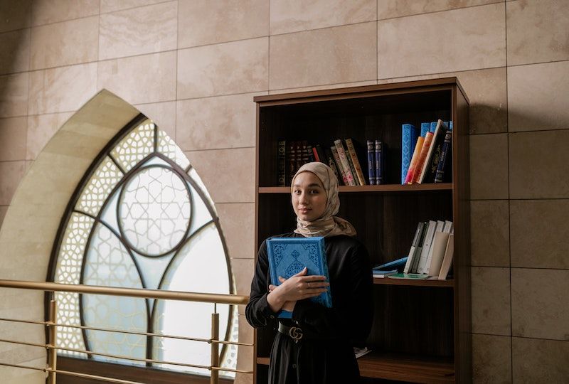 woman standing near brown wooden book shelf