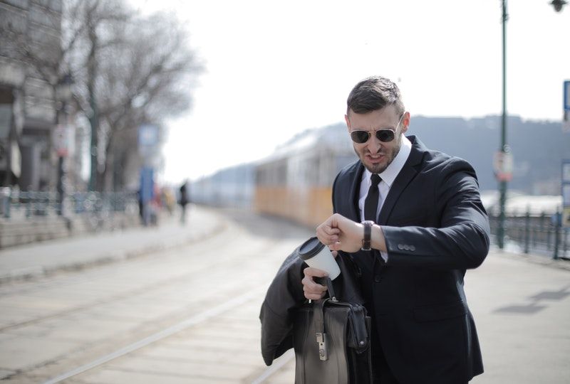 Business man at train station looks at watch