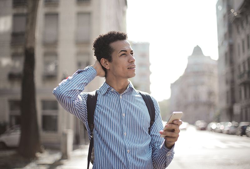 A confused man holding a cellphone