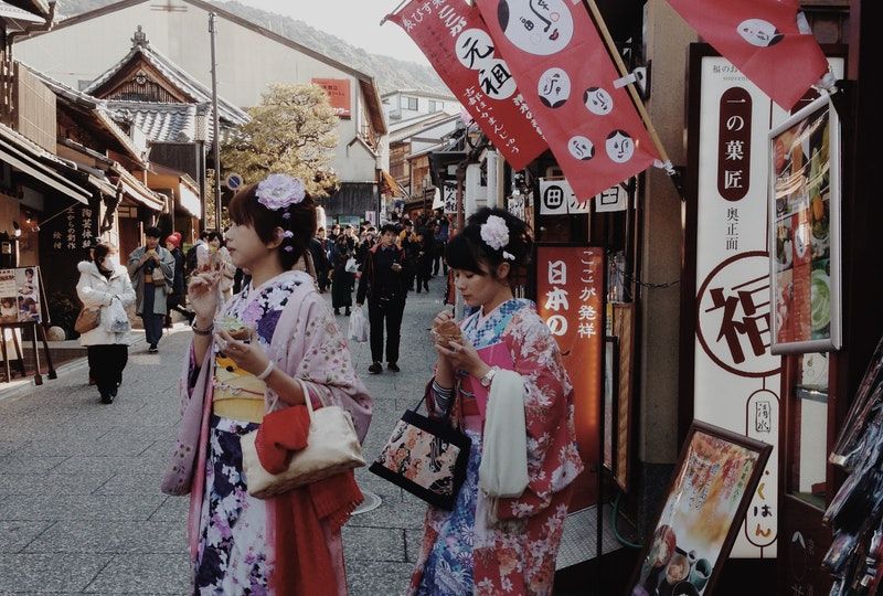 women in kimonos come out of a shop