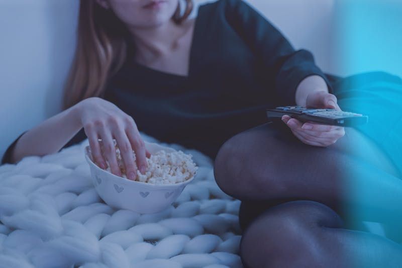 Woman watching TV with popcorn.