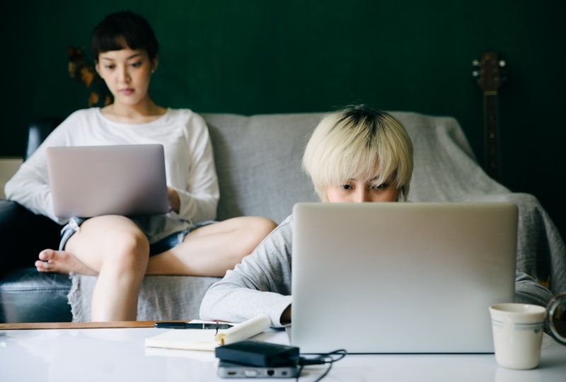 two women facing laptops