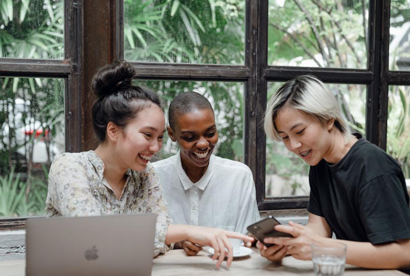 Group of people speaking and looking at phone.