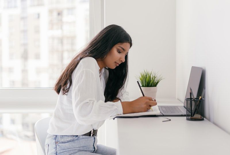 woman writing in front of her laptop