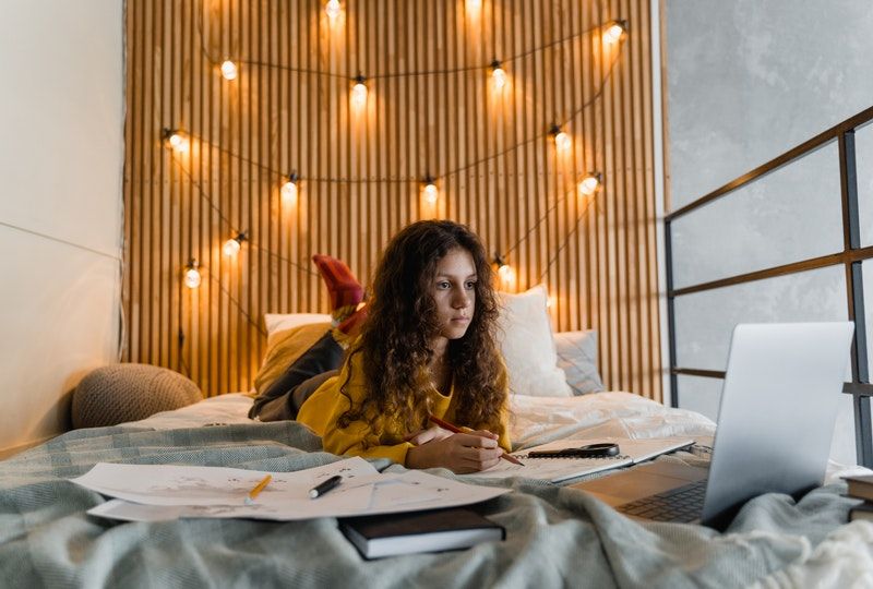 girl on the bed using laptop