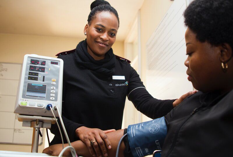 a smiling nurse taking the blood pressure of a patient