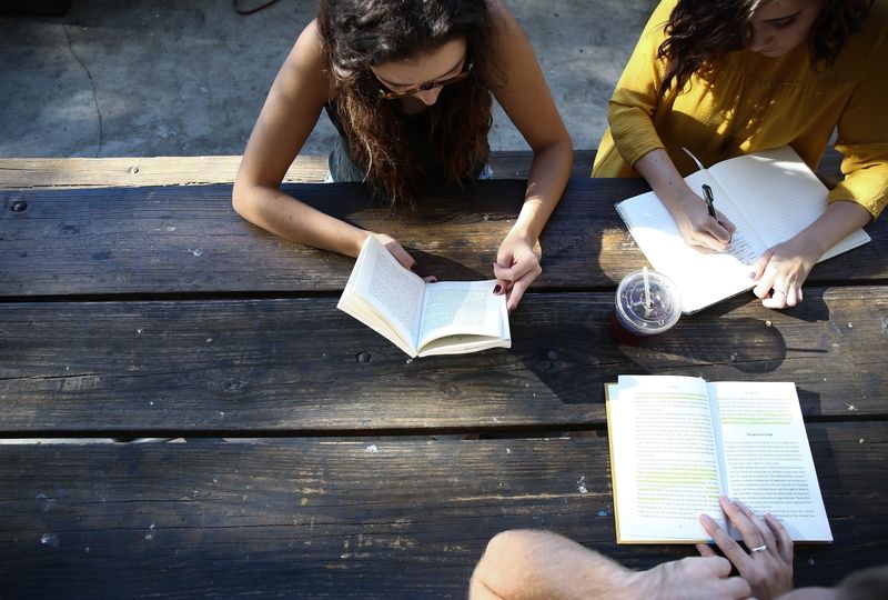 Three people studying outside at a table