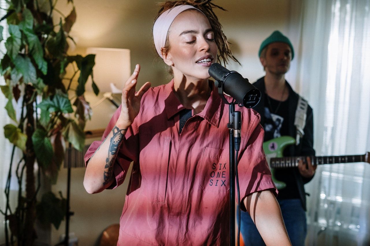 woman in pink and white plaid button up shirt holding microphone singing