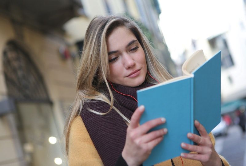 woman smiling and reading outside