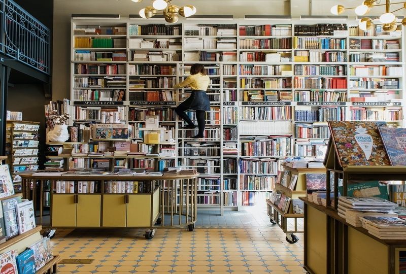 woman on a ladder looking at books