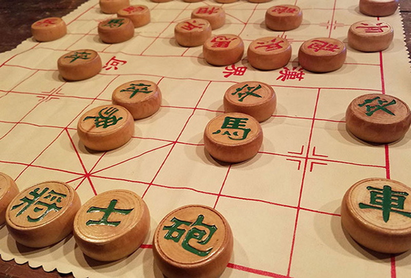 Circular wooden blocks decorated with green and red Chinese characters on a white mat with red squares on